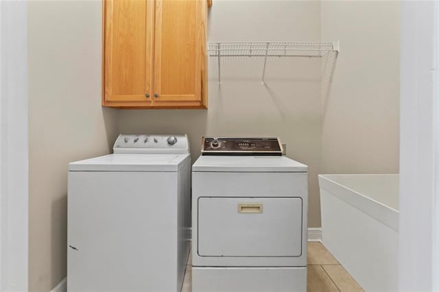 213 Secluded Oaks Ln, Madisonville, LA 70447 - laundry area with cabinet space, washer and clothes dryer, light tile patterned floors, and baseboards