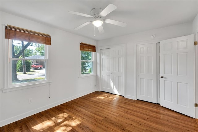 343 Lake Ave, Metairie, LA 70005 - unfurnished bedroom featuring multiple windows, two closets, light wood-style floors, and baseboards