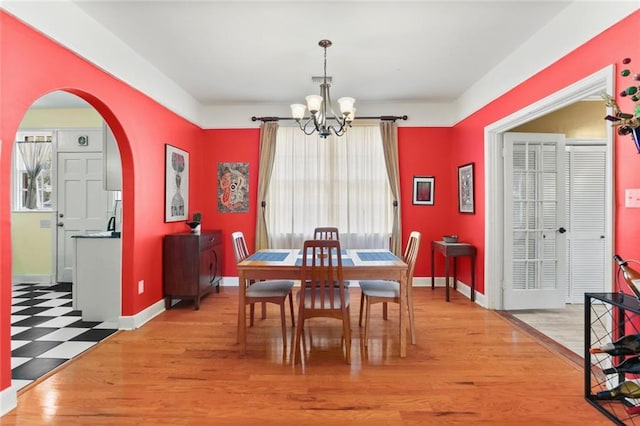 5800 Memphis St, New Orleans, LA 70124 - dining room featuring arched walkways, a chandelier, light wood-style flooring, and baseboards