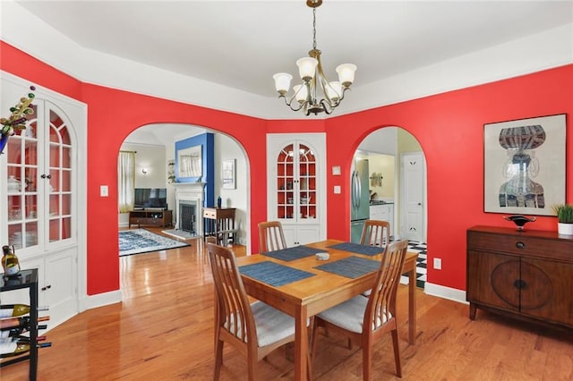 5800 Memphis St, New Orleans, LA 70124 - dining space featuring arched walkways, wood finished floors, a chandelier, a fireplace, and baseboards