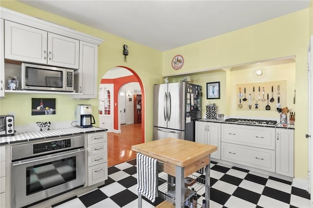 5800 Memphis St, New Orleans, LA 70124 - kitchen featuring dark flooring, appliances with stainless steel finishes, arched walkways, and white cabinets