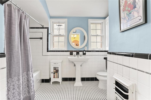 5800 Memphis St, New Orleans, LA 70124 - bathroom with tile walls, heating unit, toilet, wainscoting, and shower / bath combination with curtain