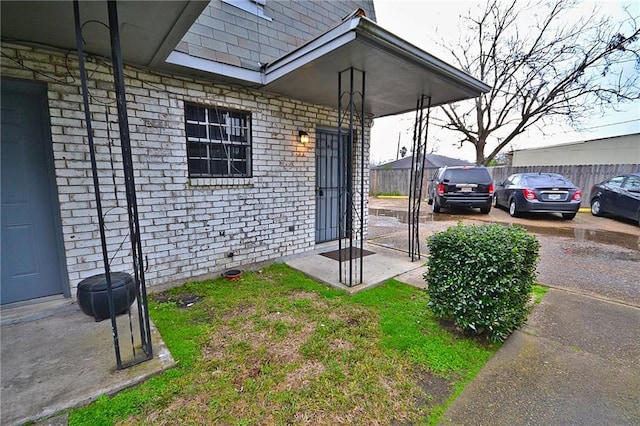 doorway to property with brick siding and fence