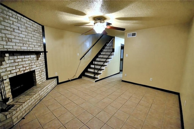 unfurnished living room with a ceiling fan, a textured ceiling, a fireplace, stairs, and baseboards