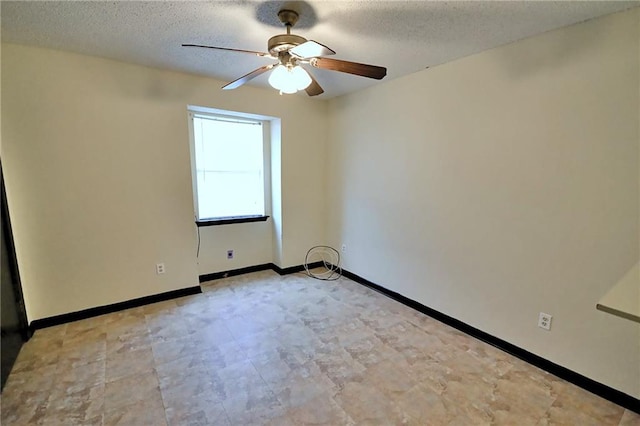 empty room with a ceiling fan, a textured ceiling, and baseboards