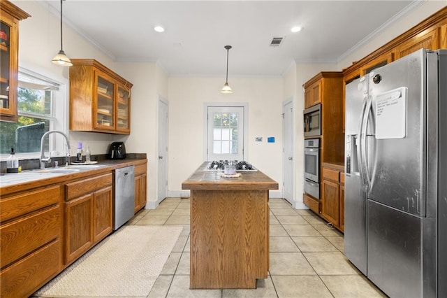 42262 Yokum Rd, Ponchatoula, LA 70454 - kitchen with stainless steel appliances, a center island, brown cabinetry, crown molding, and glass insert cabinets