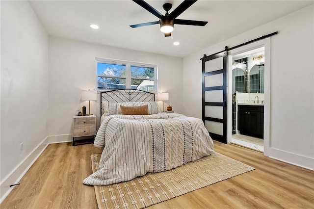 5116 Wilson Dr, Metairie, LA 70003 - bedroom featuring a barn door, wood finished floors, ensuite bathroom, baseboards, and recessed lighting