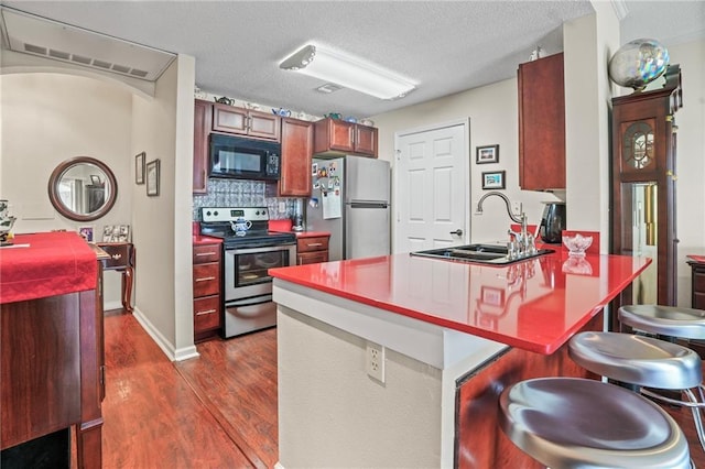 350 Emerald Forest Blvd Unit 17102, Covington, LA 70433 - kitchen with stainless steel appliances, a sink, dark wood-type flooring, a peninsula, and a breakfast bar