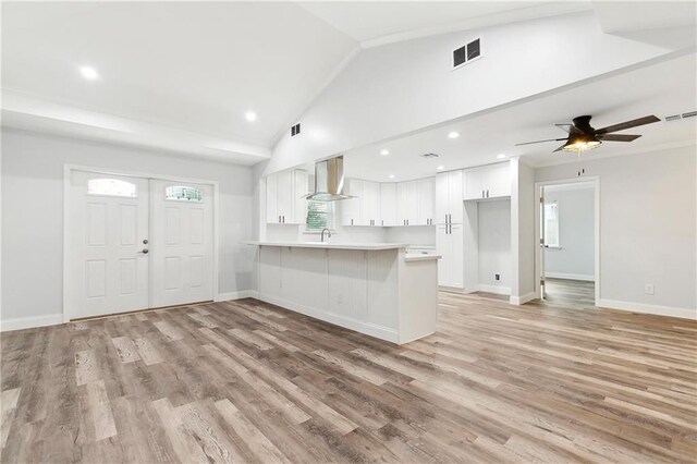 400 Sophia St, River Ridge, LA 70123 - kitchen with wall chimney range hood, a peninsula, white cabinetry, light countertops, and lofted ceiling