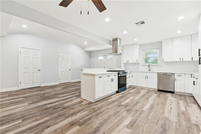 400 Sophia St, River Ridge, LA 70123 - kitchen featuring stainless steel appliances, wall chimney exhaust hood, a peninsula, light wood-style floors, and a ceiling fan