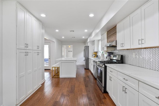 148 Macque Dr, Harahan, LA 70123 - kitchen with appliances with stainless steel finishes, under cabinet range hood, a sink, tasteful backsplash, and white cabinetry