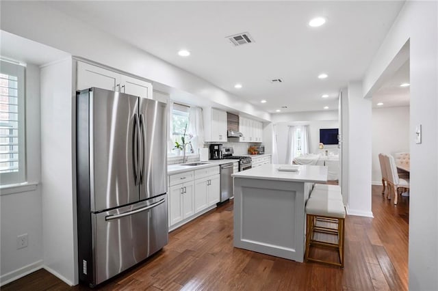 148 Macque Dr, Harahan, LA 70123 - kitchen featuring appliances with stainless steel finishes, a sink, white cabinetry, wall chimney exhaust hood, and a kitchen island