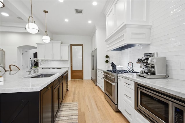 3117 39th St, Metairie, LA 70001 - kitchen featuring premium appliances, a sink, backsplash, arched walkways, and white cabinetry