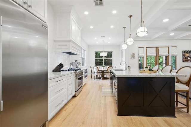 3117 39th St, Metairie, LA 70001 - kitchen featuring high quality appliances, recessed lighting, light wood-type flooring, a kitchen island with sink, and white cabinetry