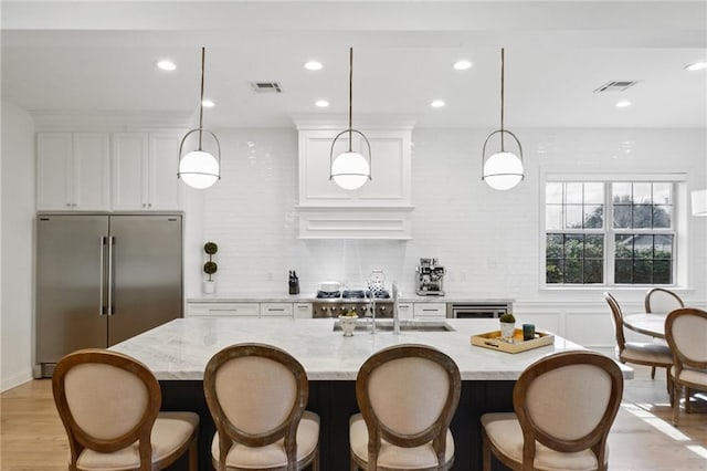 3117 39th St, Metairie, LA 70001 - kitchen featuring stainless steel built in refrigerator, a sink, white cabinets, light wood finished floors, and light stone countertops