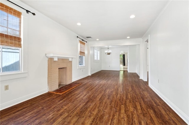 unfurnished living room with a chandelier, dark wood finished floors, baseboards, ornamental molding, and a fireplace