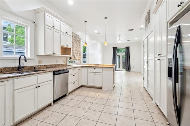 5820 Magnolia St, New Orleans, LA 70115 - kitchen featuring stainless steel appliances, a sink, a peninsula, light tile patterned flooring, and white cabinetry