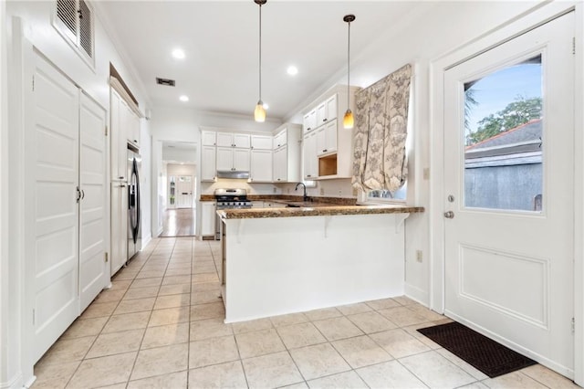 5820 Magnolia St, New Orleans, LA 70115 - kitchen featuring a peninsula, appliances with stainless steel finishes, light tile patterned floors, a kitchen bar, and a sink