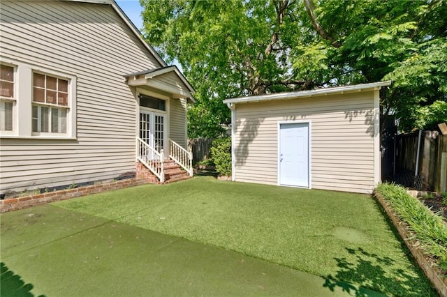 view of yard with entry steps, an outdoor structure, and french doors
