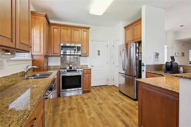 101 Portrush Dr, La Place, LA 70068 - kitchen featuring appliances with stainless steel finishes, a sink, light stone countertops, and brown cabinets