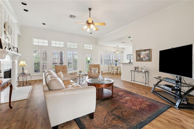 101 Portrush Dr, La Place, LA 70068 - living area featuring ceiling fan, wood finished floors, a tiled fireplace, ornamental molding, and baseboards