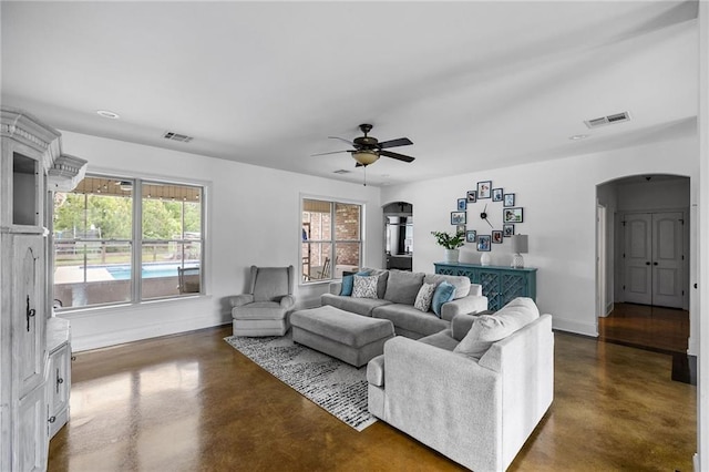 living room with arched walkways, concrete flooring, baseboards, and recessed lighting