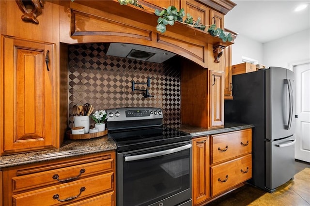 kitchen featuring electric range, decorative backsplash, freestanding refrigerator, and brown cabinets