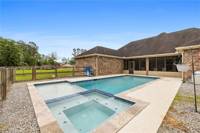 view of swimming pool with a pool with connected hot tub, a fenced backyard, and a sunroom