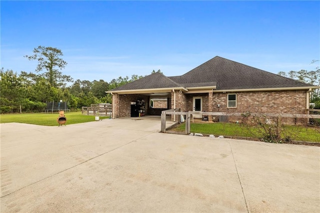 view of front of house with a trampoline, a front lawn, concrete driveway, and brick siding