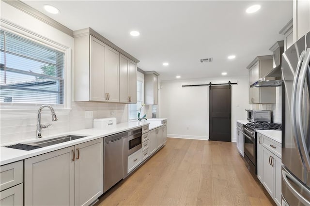 7449 Cameo St, New Orleans, LA 70124 - kitchen with stainless steel appliances, a barn door, a sink, decorative backsplash, and recessed lighting