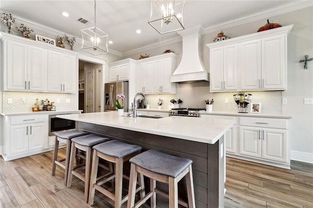 2040 Cypress Bend Ln, Madisonville, LA 70447 - kitchen with custom range hood, a sink, stainless steel appliances, a chandelier, and a kitchen bar