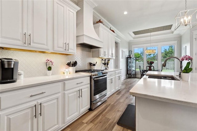 2040 Cypress Bend Ln, Madisonville, LA 70447 - kitchen featuring stainless steel gas range, custom range hood, a sink, light wood finished floors, and a tray ceiling