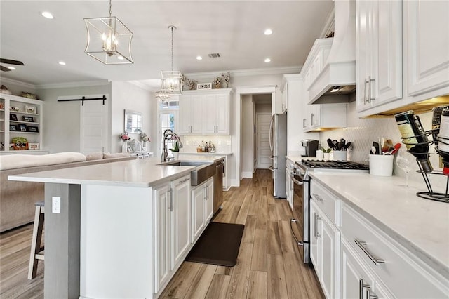 2040 Cypress Bend Ln, Madisonville, LA 70447 - kitchen featuring appliances with stainless steel finishes, a barn door, premium range hood, ornamental molding, and white cabinetry
