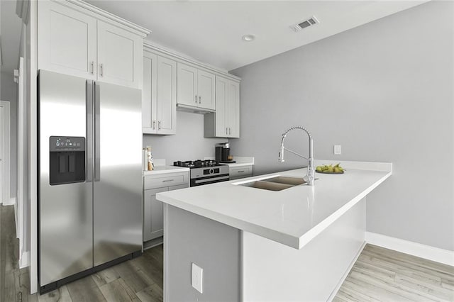 2830-32 Spain St, New Orleans, LA 70122 - kitchen with appliances with stainless steel finishes, light wood-style floors, a peninsula, and light countertops
