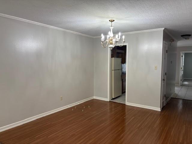 138 Woodland Ridge Dr, Mccomb, MS 39648 - spare room with a chandelier, wood finished floors, ornamental molding, baseboards, and a textured ceiling