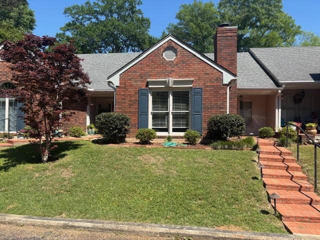 138 Woodland Ridge Dr, Mccomb, MS 39648 - view of front of house featuring a front yard, a chimney, a shingled roof, and brick siding