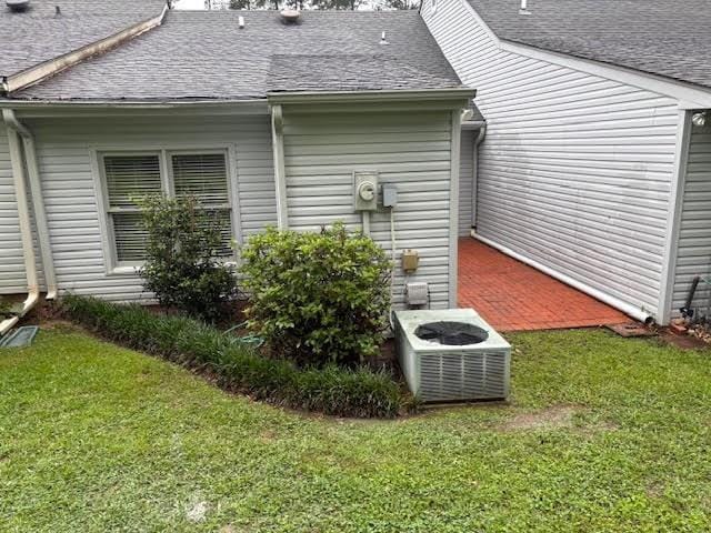 138 Woodland Ridge Dr, Mccomb, MS 39648 - view of side of home featuring roof with shingles, a lawn, and central AC