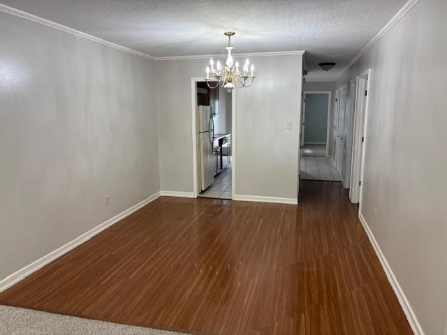 138 Woodland Ridge Dr, Mccomb, MS 39648 - unfurnished dining area with a chandelier, wood finished floors, ornamental molding, baseboards, and a textured ceiling