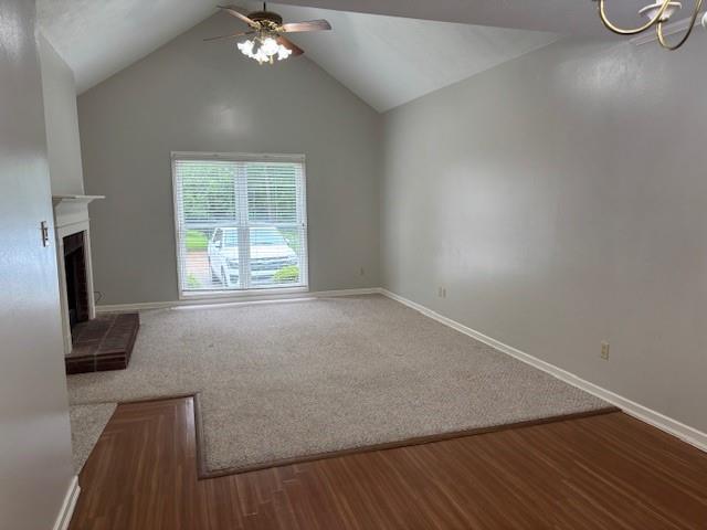 138 Woodland Ridge Dr, Mccomb, MS 39648 - unfurnished living room featuring a ceiling fan, baseboards, vaulted ceiling, carpet, and a fireplace with raised hearth