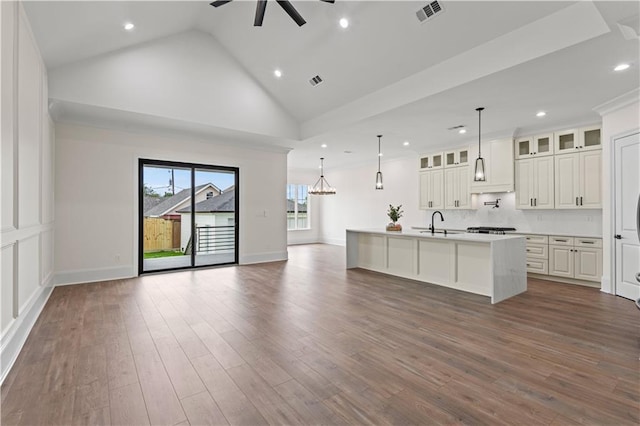 unfurnished living room with a ceiling fan, recessed lighting, dark wood finished floors, a sink, and high vaulted ceiling