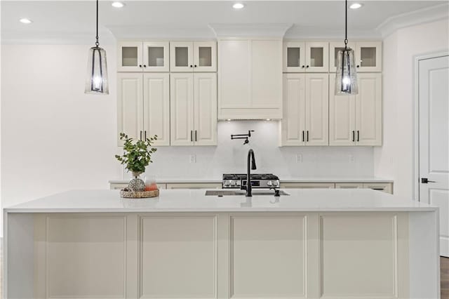 kitchen with a sink, a kitchen island with sink, light countertops, decorative backsplash, and recessed lighting