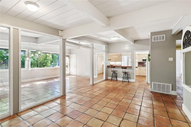 unfurnished living room featuring beamed ceiling, baseboards, and light tile patterned floors