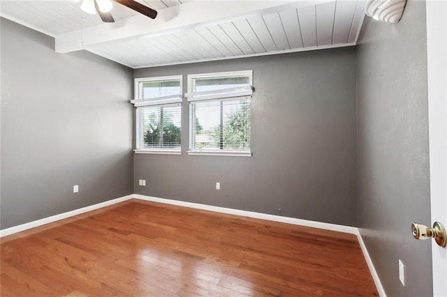 unfurnished room featuring ceiling fan, beam ceiling, wood finished floors, baseboards, and wooden ceiling
