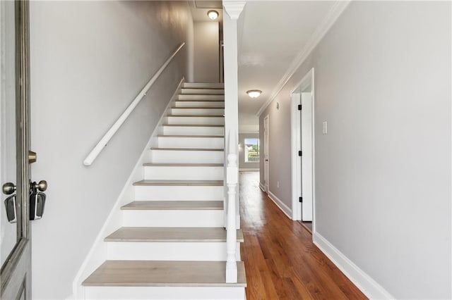 stairs with ornamental molding, wood finished floors, and baseboards