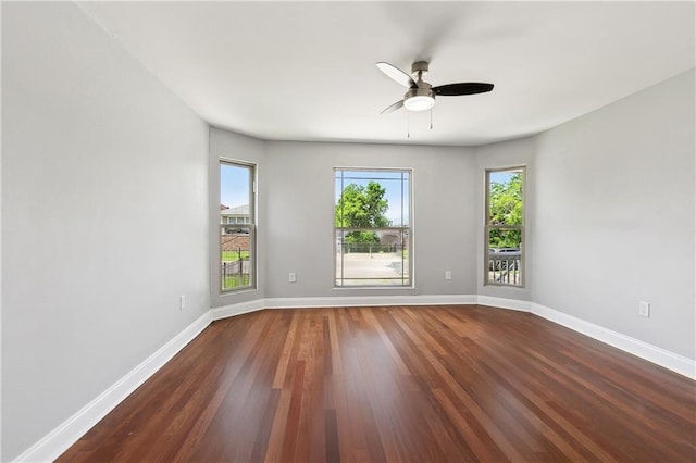 spare room with dark wood-style floors, baseboards, and a ceiling fan