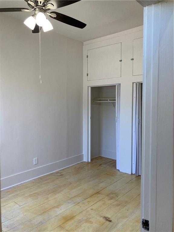 3515 S Miro St, New Orleans, LA 70125 - unfurnished bedroom with light wood-style flooring, baseboards, a closet, and a ceiling fan