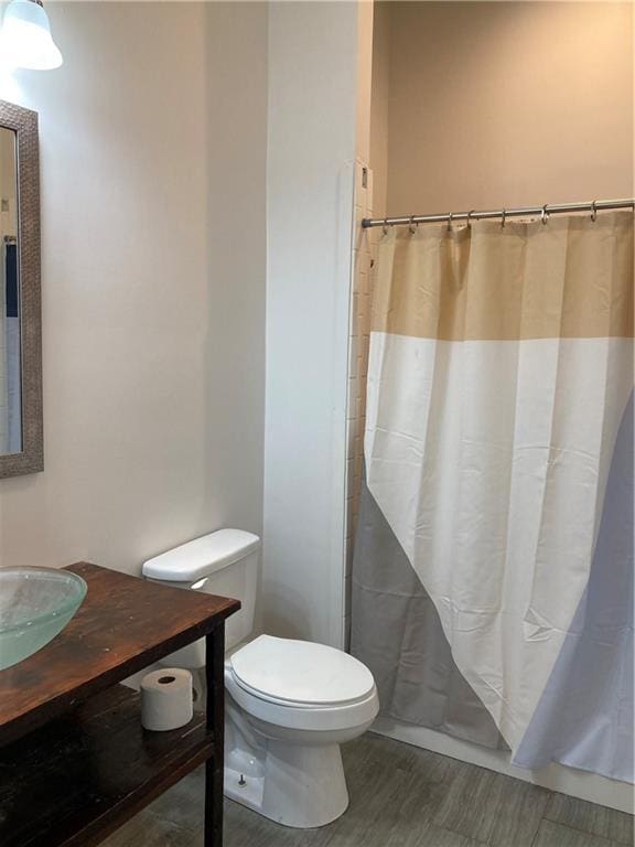 3515 S Miro St, New Orleans, LA 70125 - full bathroom with toilet, wood finished floors, vanity, and a shower with curtain