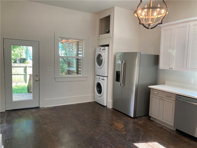 3515 S Miro St, New Orleans, LA 70125 - kitchen with appliances with stainless steel finishes, stacked washer / drying machine, a chandelier, light countertops, and white cabinetry