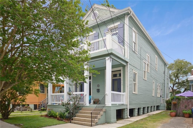 view of front of house featuring a balcony, covered porch, and a front yard
