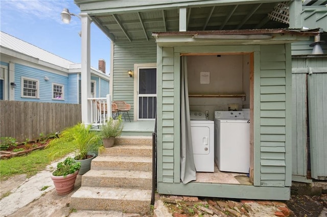 entrance to property featuring washer and dryer and fence
